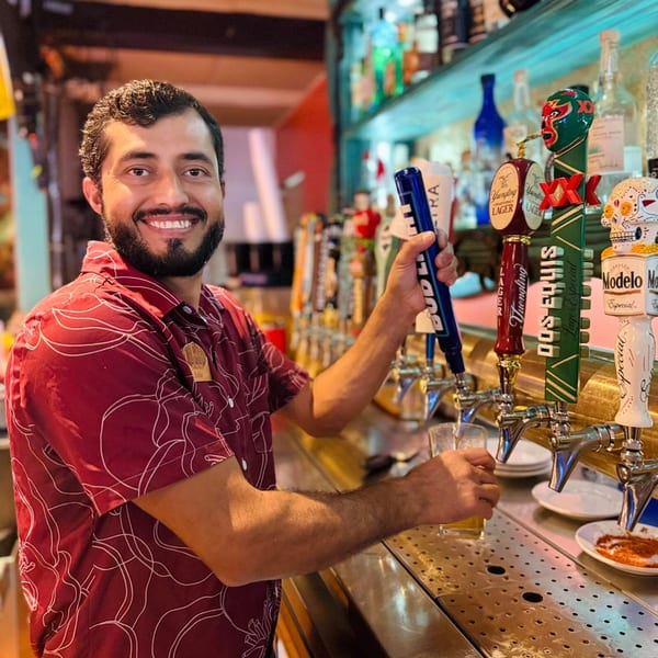 Smiling bartender Eddie pouring a beer from a tap at El Leoncito, a Mexican restaurant.