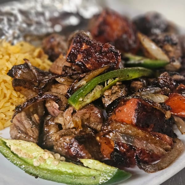 El Leoncito's grilled steak with onions, red peppers, jalapeños, and yellow rice.