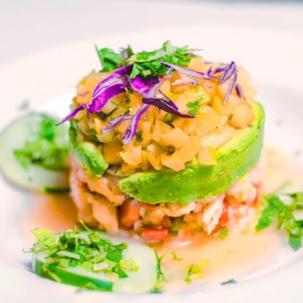 El Leoncito's vibrant ceviche tower with avocado, shrimp, and red cabbage on a white plate.